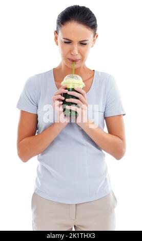 Non so di questo...Studio shot di una donna che beve un frullato di erba del grano. Foto Stock