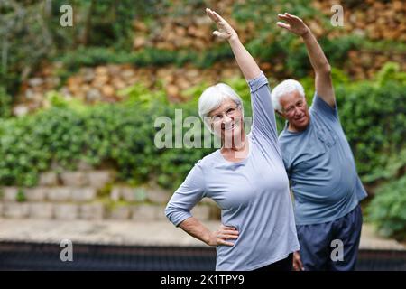 È importante rimanere attivi in età avanzata: Una coppia anziana che fa yoga insieme all'aperto. Foto Stock