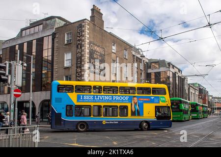 Dublin Bus che viaggia sotto i cavi del tram LUAS a Dublino, Irlanda. Foto Stock