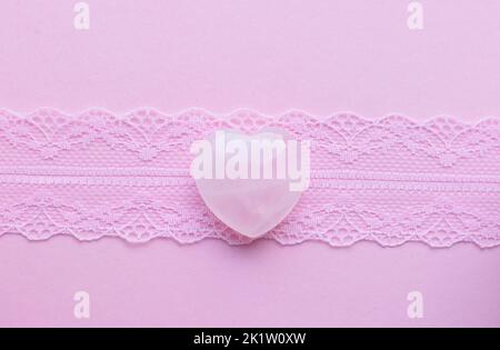 Cristalli di quarzo rosa a forma di cuore su pizzo rosa. I minerali semi-preziosi sono un talismano d'amore per le donne. Foto Stock