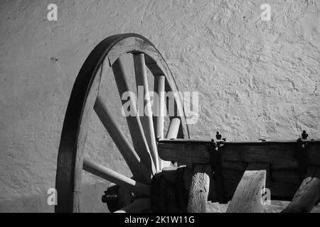 Un colpo in bianco e nero di una ruota di un rustico carrello di legno Foto Stock