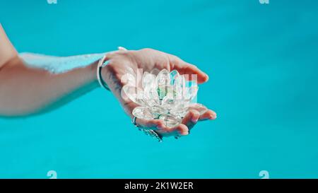 Donna che tiene fragile fiore di loto. Gocce d'acqua pulite gocciolano dal cristallo. Concetto di religione, kundalini, meditazione, chakra, interiore spirituale Foto Stock