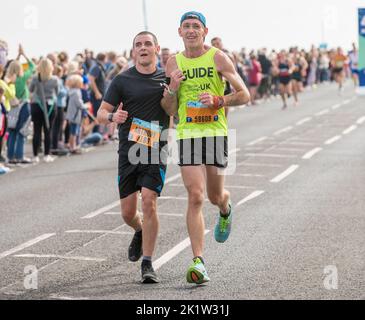 Runner dell'organizzazione Guide Running uk aiuta a sostenere un runner che partecipa alla mezza maratona Great North Run 2022 Foto Stock