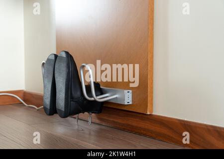Scarpe nere essiccate su un essiccatore elettrico vista laterale ravvicinata Foto Stock