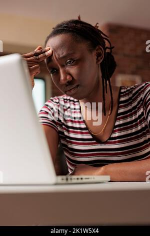 Studente stanco stressato che ha emicrania, guardando lo schermo del notebook, che soffre di sintomi di mal di testa, sfregamento della fronte. Il lavoratore remoto esausto si sente malcontento, il freelancer insoddisfatto di lavorare Foto Stock