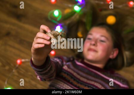 Defocus Natale ragazza tenendo regalo sul pavimento. Top sopra la vista ad angolo alto foto di felice giovane donna tenere le mani viso natale pavimento regali all'interno Foto Stock