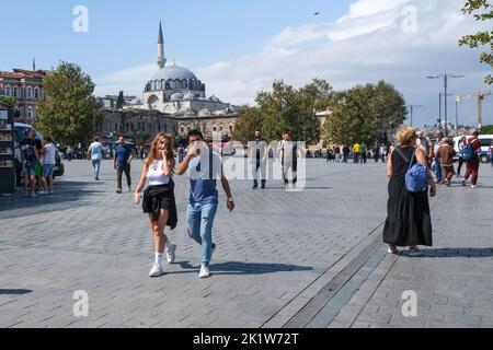 Le coppie camminano intorno alla piazza con una vista sullo sfondo della Moschea di Rüstem Pasha vicino al bazar. Situato nel quartiere Eminönü di Istanbul, lo storico Bazaar delle spezie continua ad essere un centro commerciale preferito dai turisti locali e stranieri. E' un luogo distinto dove turisti da tutto il mondo possono fare acquisti e gustare prelibatezze specifiche del paese. Foto Stock