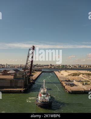 Europa, Francia, Dunkerque - 9 luglio 2022: Il rimorchiatore entra nella chiusa del Canal de Bourbourg per raggiungere gli impianti portuali. Aprire il ponte verticale e la collectio Foto Stock