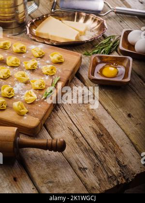 Cottura di gnocchi fatti in casa, ravioli con ripieno di carne. Su un tagliere infarinato, gnocchi crudi, ravioli, ingredienti su un fondo di legno. Ricetta Foto Stock