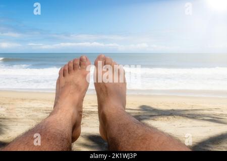 Un piede sulla spiaggia con il mare e cielo blu sullo sfondo con copyspace Foto Stock