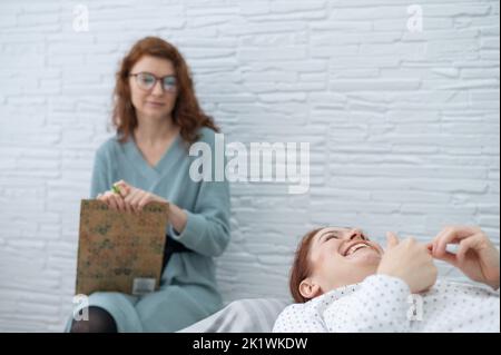 Una donna di mezza età si trova su un divano e parla con uno psicologo. Foto Stock