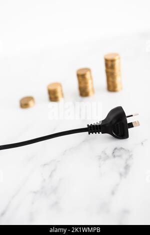 i costi dell'elettricità aumentano l'immagine concettuale, si inseriscono con pile crescenti di monete nel backgroung che rappresentano i prezzi che aumentano Foto Stock