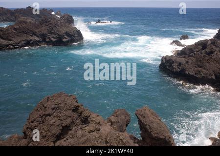 Aspre rocce vulcaniche colpite da onde provenienti dall'oceano Atlantico a Seixal, sulla costa settentrionale di Madeira Foto Stock