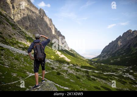 Un'inquadratura a basso angolo della piccola valle di Tarpataki con una vista posteriore dell'uomo a piedi, cielo blu sullo sfondo Foto Stock