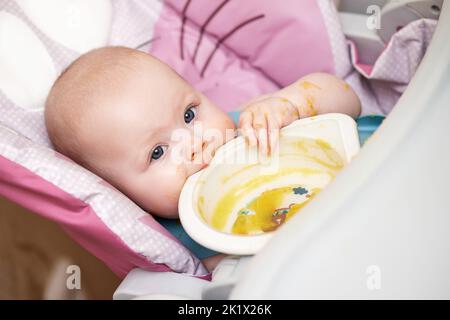 bambina che mangia con il cucchiaio in cucina Foto Stock