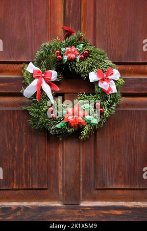 Corona di Natale sulla porta rossa di legno Foto Stock