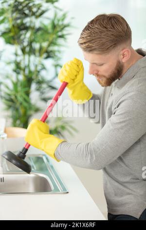 Pulizia tubi ostruiti nel lavello da cucina con uno stantuffo Foto Stock