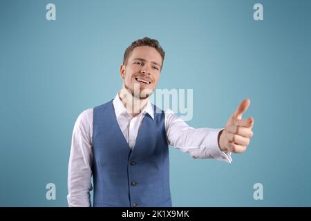Giovane uomo d'affari con barba su sfondo blu isolato gesturing con le mani in camicia bianca e blu gilet, ragazzo emotivo caucasico ufficio lavoratore Foto Stock