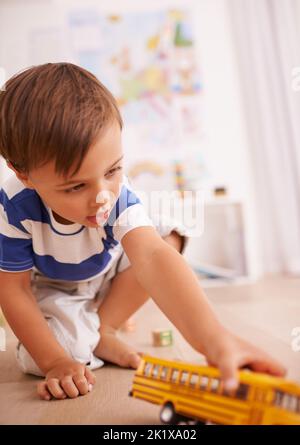 Scopa scopa. Un ragazzino carino che gioca con un giocattolo giallo nella sua stanza. Foto Stock