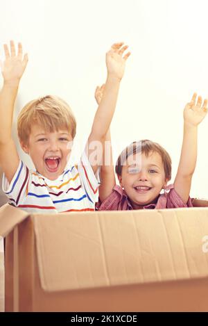 Siete ragazzi pronti a guidare. Due giovani fratelli alzano le braccia mentre saltano fuori da una scatola di cartone. Foto Stock