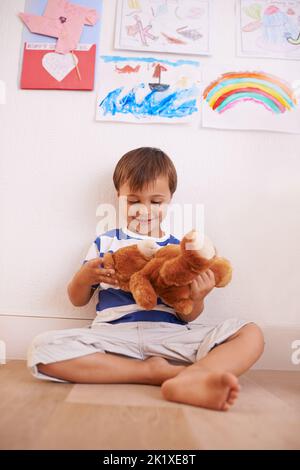 Momenti di divertimento con il teddy. Un ragazzino che gioca con il suo orsacchiotto in camera. Foto Stock