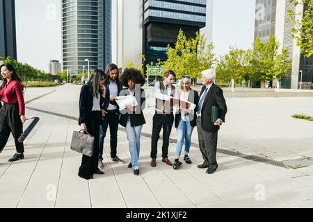 Uomini d'affari multietnici che lavorano all'aperto dall'edificio degli uffici Foto Stock