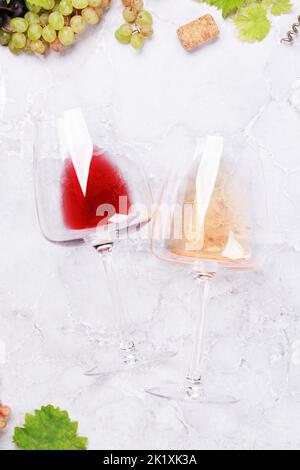 Bicchieri da vino rosso e rosa e uva. Giacitura piatta Foto Stock