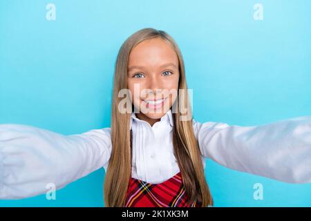 Selfie closeup foto della giovane bambina scolastica prendere cadre dalla lezione di scuola sorriso positivo isolato su sfondo di colore blu Foto Stock