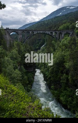 Overdalen, Norvegia - 01 luglio 2022: Kylling Bru è un ponte ferroviario in pietra scavata a mano. La linea Rauma attraversa il ponte di Verma, in cima Foto Stock