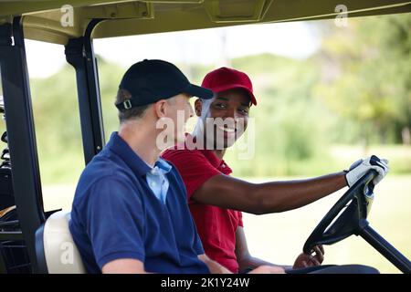 Perché camminare quando si può guidare. Due uomini felici che guida un golf cart su un campo da golf. Foto Stock