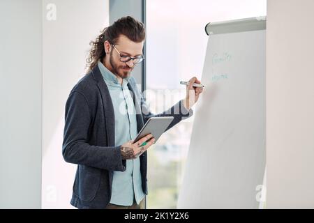Un giovane insegnante scrive lezioni a bordo per gli studenti in classe. Foto Stock