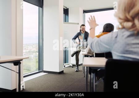 Gli anziani sono seduti in classe, alzando le mani e facendo domande sulla lezione loro educatore. Foto Stock
