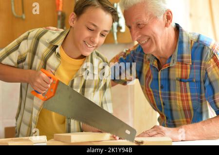 Falegname anziano e suo nipote in officina Foto Stock