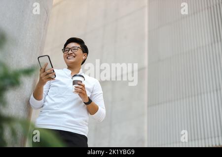 Sorridente giovane utilizzando il telefono cellulare Foto Stock