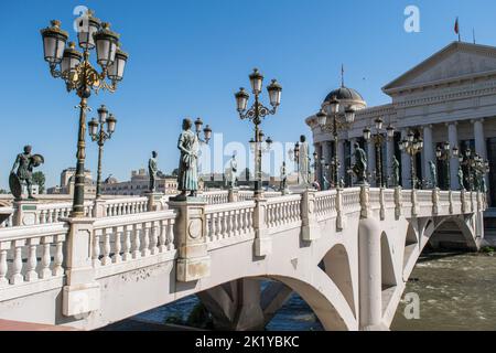 Statue che decorano il Ponte delle civiltà, di fronte al Museo Archeologico di Skopje, Macedonia settentrionale. Ponte che attraversa il fiume Vardar, in estate. Foto Stock