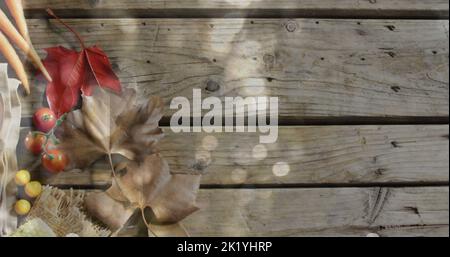 Immagine di macchie di luce su posate e foglie su sfondo di legno Foto Stock