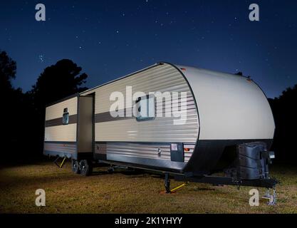 Rimorchio di viaggio su un campo erboso con stelle luminose sopra di notte Foto Stock