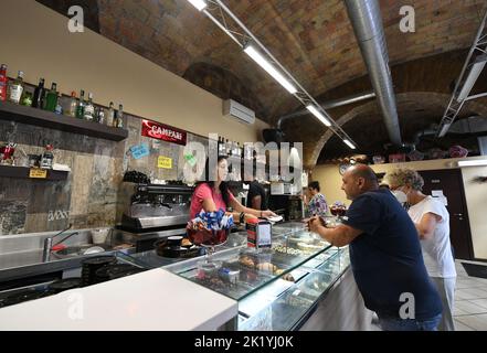 (220921) -- ROMA, 21 settembre 2022 (Xinhua) -- Sara (1st L), figlia di Laura Ramoni, serve cibo per i clienti al bar Big Mamy di Roma, 17 settembre 2022. Al bar Big Mamy di Roma, un manichino gonfiabile appeso alla finestra portava un cartello giallo con la scritta "The Bill has arrived" (il conto è arrivato). Laura Ramoni, proprietaria del bar, ha detto a Xinhua che la bolletta elettrica del bar a giugno e luglio era di circa 2.600 euro, che quasi triplicavano rispetto allo stesso periodo dell'anno scorso. "Non possiamo pagare il conto", ha detto. "Devo licenziare due persone che hanno lavorato qui, e ho aumentato il prezzo del caffè di 0,1 dollari Foto Stock