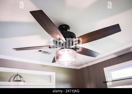 Un soffitto con vassoio bianco con un moderno ventilatore di legno scuro e pareti marroni Foto Stock