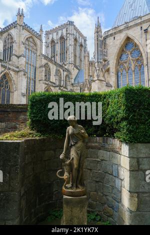 Treasurer's House Garden con la statua femminile Fidelity con il braccio sollevato in un'istruzione a un cane e York Minster sullo sfondo, York, Regno Unito. Foto Stock