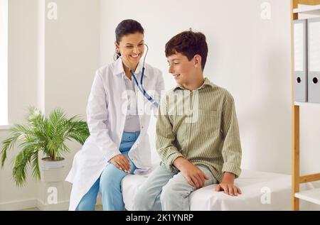 Bambino piccolo felice ottenere un controllo del cuore o dei polmoni all'ufficio del pediatra Foto Stock