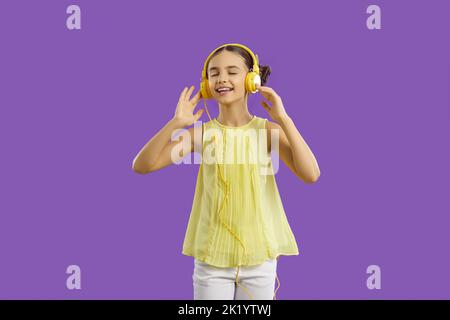 Felice ragazza caucasica adolescente in cuffie godere di ascoltare le canzoni preferite stand in studio Foto Stock