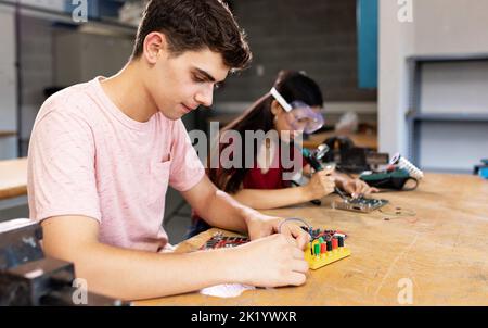 Diversi giovani studenti delle scuole superiori che imparano nella classe elettronica di robotica scientifica Foto Stock