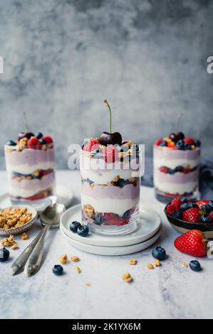 Primo piano di parfait misti di yogurt bacca su sfondo grigio. Foto Stock