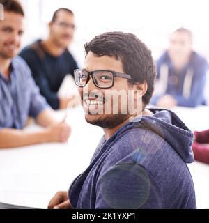 Il team tecnico dei tuoi sogni. Ritratto di un giovane felice seduto in un incontro con i suoi colleghi. Foto Stock