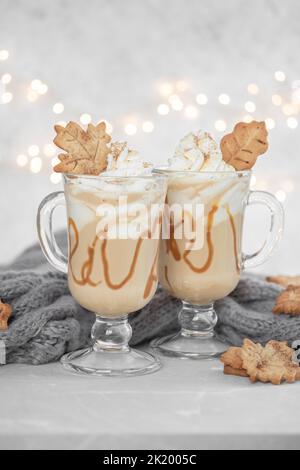 Latte di spezie di zucca in una tazza di vetro con caramello e cannella con decorazione autunnale Foto Stock