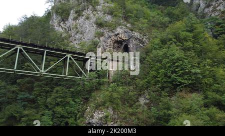 Vista dall'alto di un vecchio ponte ferroviario collegato ad un tunnel su una montagna