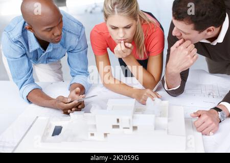 Al tavolo degli architetti... Un gruppo di architetti che lavorano insieme su un modello architettonico. Foto Stock