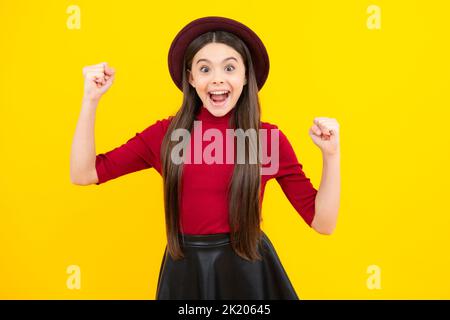 Adolescente eccitato, contento stupito e overjoyed emozioni. Ritratto di gioiosa bambina con mani sollevate. Adolescente caucasico urlando isolato su giallo Foto Stock