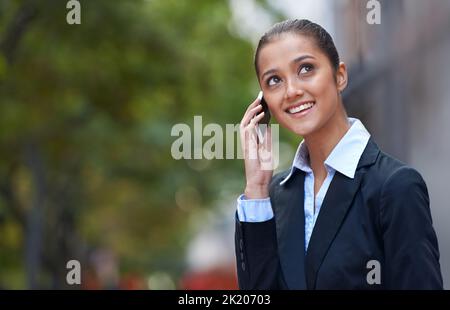 Restare connessi in movimento. Un colpo di una giovane donna d'affari che parla sul suo cellulare in città. Foto Stock